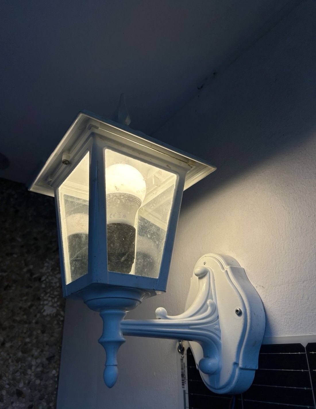 Eingeschaltete weiße Außenwandleuchte bei einem warmen Lichttest